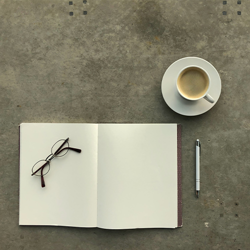 Book, pen, glasses, and a hot cup of coffee on a concrete floor | Coor