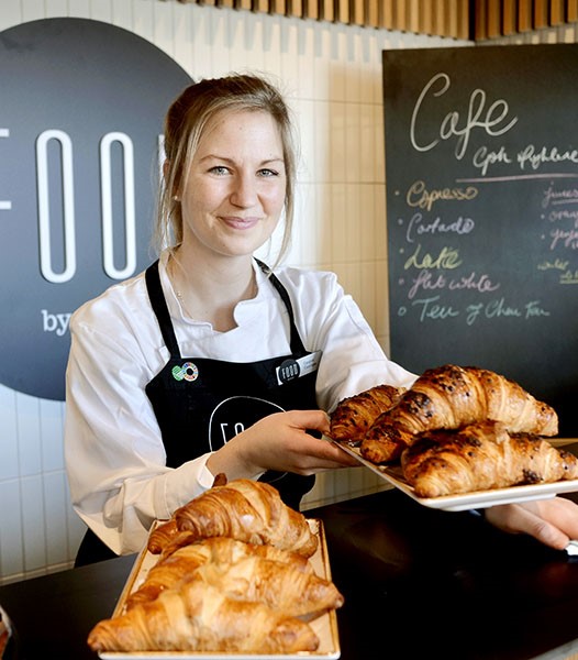 Woman in apron holding croissants