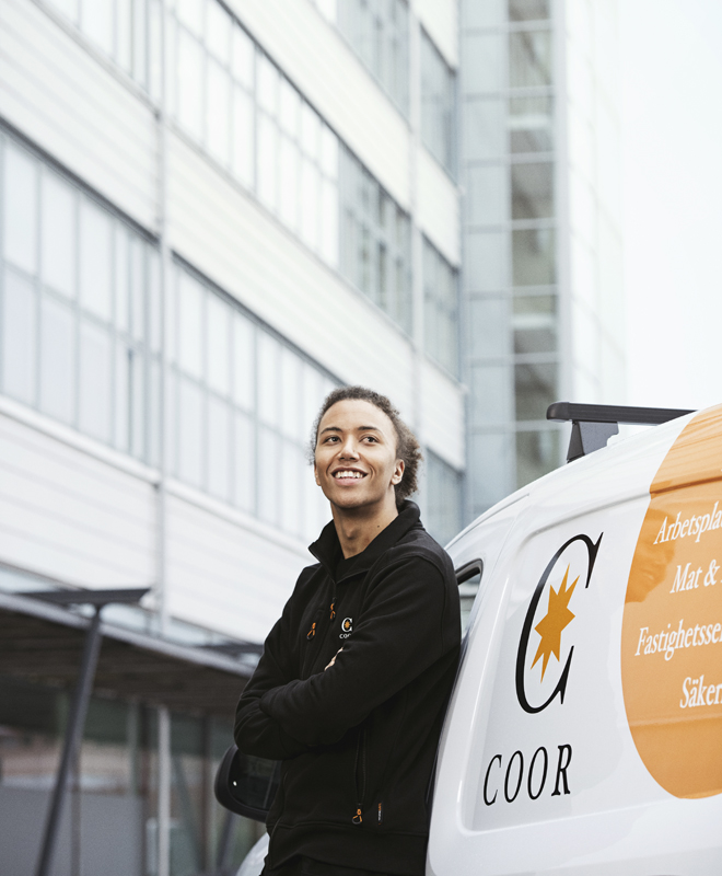 Employee standing in front of a van with Coor logo on it | Coor 