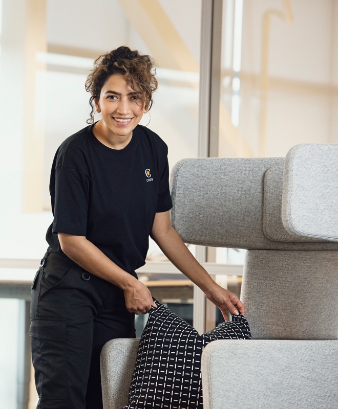 Woman putting a pillow on a chair and smiling | Coor 